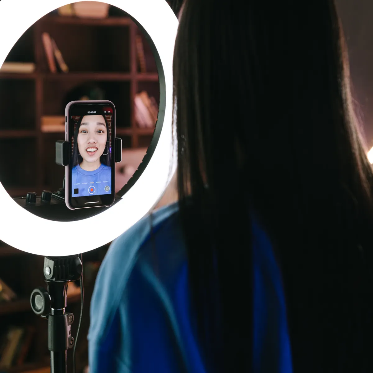 Content creator recording a video with a smartphone and studio ring light